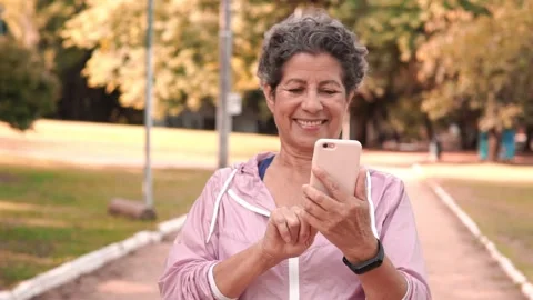 Retired woman using smart cell phone before morning run Stock Footage 168623256