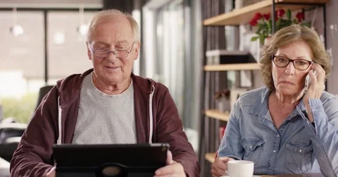 Retiree typing on tablet and using a Handy at home Stock Footage 82177978