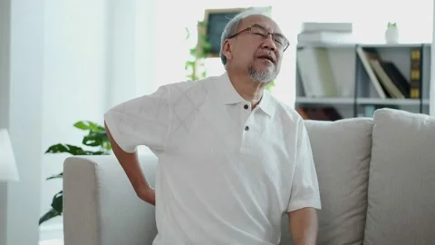 The retiring Asian elderly, sitting alone on the sofa, suffer from sudden, se Stock Footage 153247563