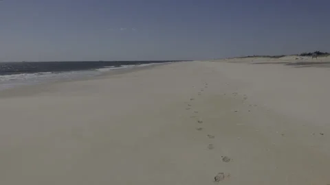 Retracing footsteps in a deserted white sand beach on a sunny day Stock Footage 218408086