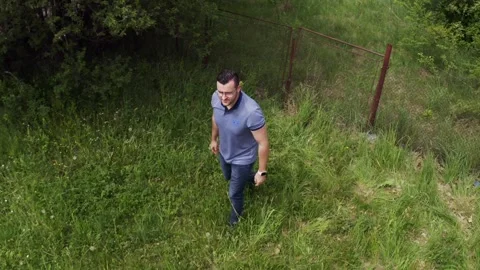 Retreating drone shot moving away from a tourist walking in a field in the Stock Footage 265991522