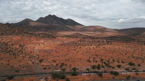 Retreating flight over dual carriageway with trucks revealing vast arid red Stock Footage 336499848