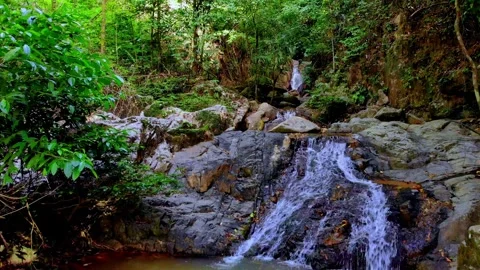 Retreating shot pulling back from rushing water cascading over flat rocks Stock Footage 340317121