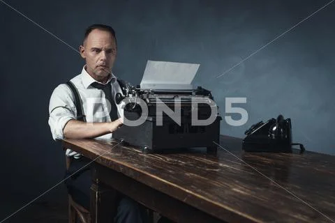 Retro 1940 office worker behind desk with typewriter and telephone. Stock Photos