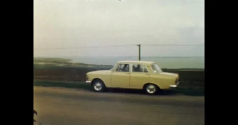 Retro 1970s road trip in Soviet Crimea, yellow car on seaside highway Stock Footage 330657096