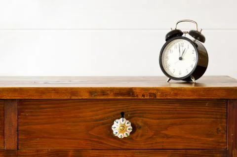 Retro alarm clock on bedside table,  background white wooden wall Stock Photos
