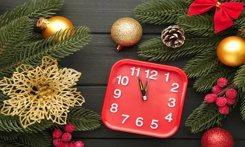 Retro alarm clock, fir branches with cones on black wooden background. Top vi Stock Photos