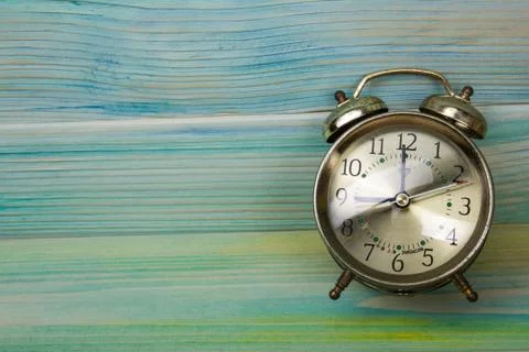 Retro alarm clock on table on mint green background 写真素材