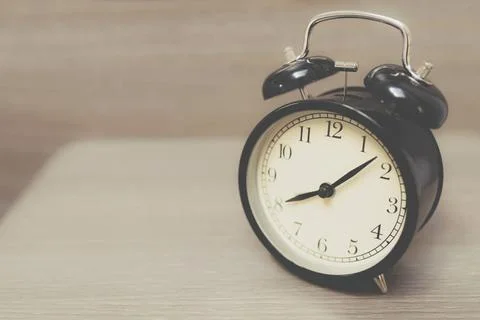  Retro alarm clock on table Retro alarm clock on table with vintage backgr... Foto stock