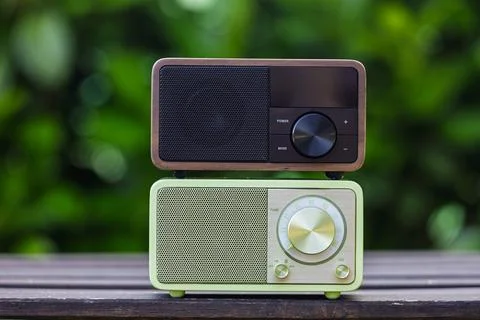 Retro and Modern Radios Side by Side Against Green Nature Background Stock Photos