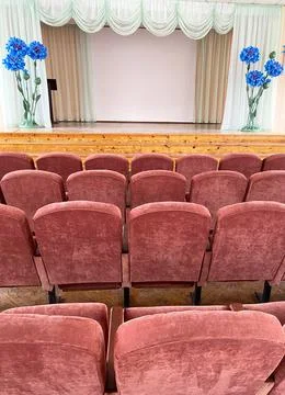Retro assembly hall featuring rows of plush pink chairs facing a wooden stage Stock Photos