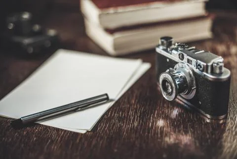 Retro camera and sheets of paper on table. Writing a story. Stock Photos