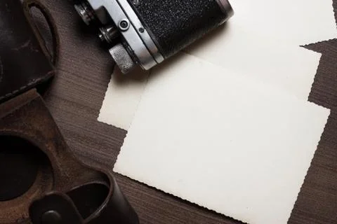 Retro camera and some old photos on brown wooden table Stock Photos
