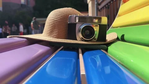 Retro camera and straw hat on colorful bench, summer vacation concept backgro Stock Footage 345151404
