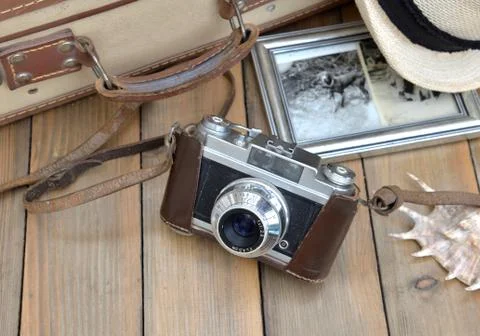 Retro camera with picture frame, hat suitcase and seashell on wooden table Stock Photos