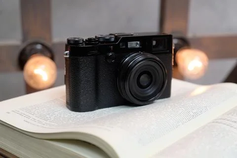Retro camera standing on an open book on the back of a wooden wall with glowi Stock Photos