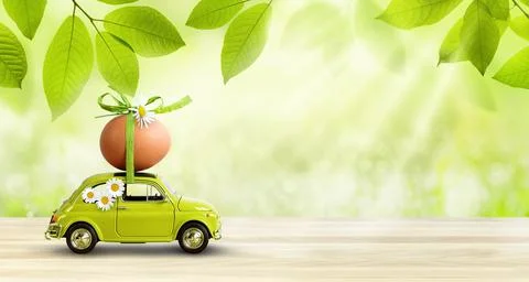 Retro car carrying an easter egg on the roof on fresh green spring foliage Stock Photos