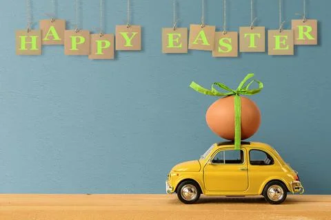 Retro car carrying an easter egg on the roof. Copy space 写真素材