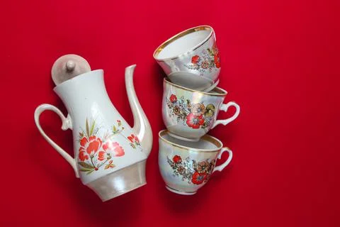 Retro ceramic teapot, stack of cups on a red background. Top view Stock Photos