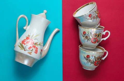 Retro ceramic teapot, stack of cups on blue red background. Top view Stock Photos
