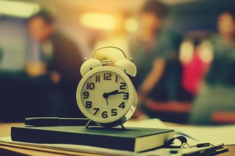 Retro clock time at 9 o'clock with notebook or memo on wood table, times of m Stock Photos