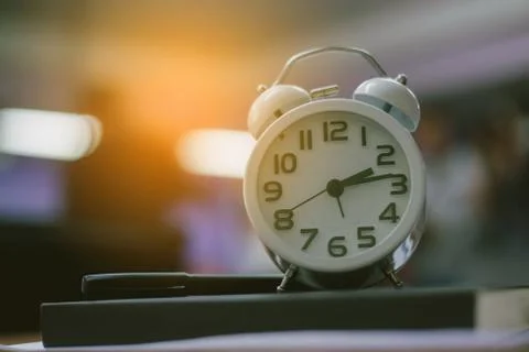 Retro clock time at 9 o'clock with notebook or memo on wood table, times of m Stock Photos