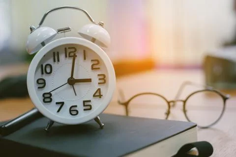Retro clock time at 9 o'clock with notebook or memo on wood table, times of m Stock Photos