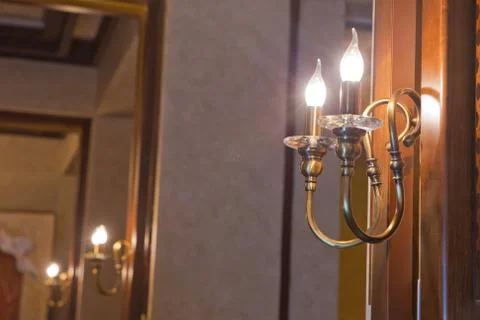 Retro copper candlestick hanging on the wall. Vintage golden candlestick with Stock Photos