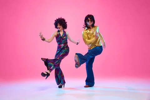 Retro disco era fashion. Couple with funky hairstyles and groovy clothes dancing Stock Photos