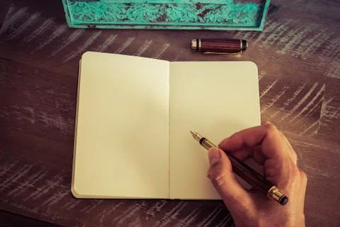 Retro effect and toned image of a woman hand writing a note with a fountain pen Stock Photos