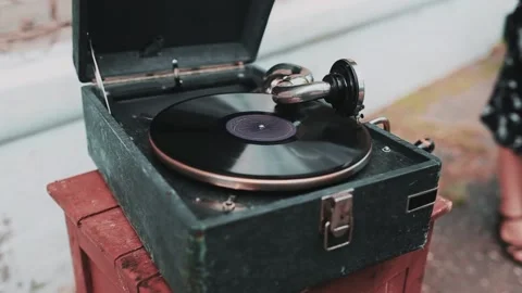 A retro gramophone with a rotating vinyl record stands on a chair outside. Video stock 155493992