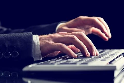 Retro image of businessman hands using office computer keyboard. Over black.. 写真素材