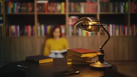 Retro lamp and stack of books on library desk, woman enjoys her reading hobby Stock Footage 342731754