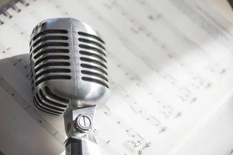 Retro microphone placed on musical notes Stock Photos
