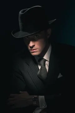 Retro mysterious gangster with hat in suit and tie. Against dark blue wall. Foto stock