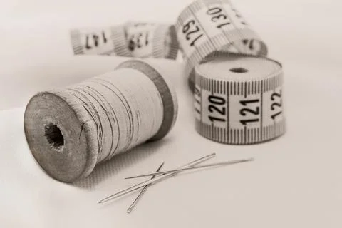 Retro needle and thread lie on the fabric. Tools for a tailor or seamstress. Stock Photos