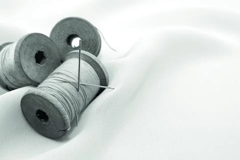 Retro needle and thread lie on the fabric. Tools for a tailor or seamstress. Stock Photos
