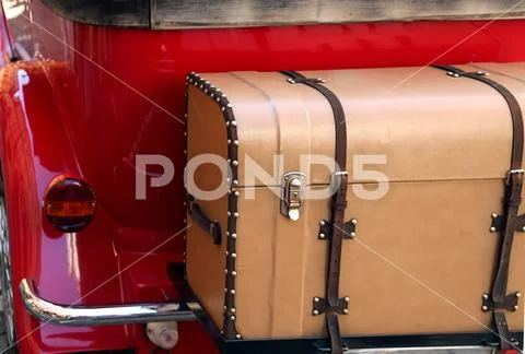 Retro old leather trunk attached to the red vintage car Stock Photos