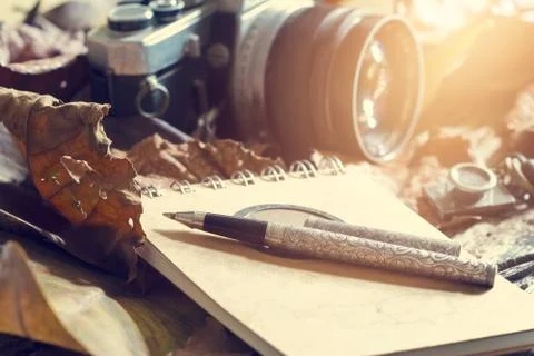 Retro pen on old note pad and camera on dry leaf in jungle background Stock-Fotos