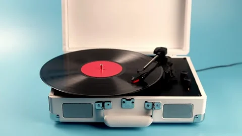 Retro portable record player with vinyl spinning on a blue background Stock Footage 339275642