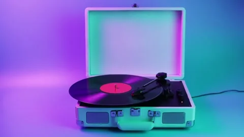 Retro portable record player with vinyl spinning under vibrant neon lights Stock Footage 339275811