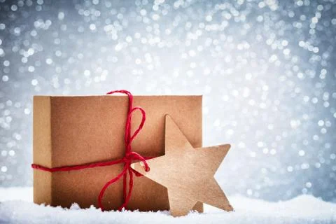 Retro rustic Christmas gift, present in snow on glitter background Stock-Fotos