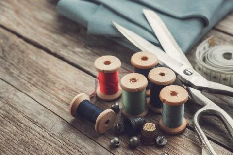 Retro sewing items: tailoring scissors, thimbles, buttons, thread spoons. Stock Photos