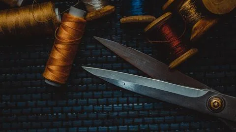 Retro sewing items: tailoring scissors, cutting knife, thimble, wooden thread Stock Photos