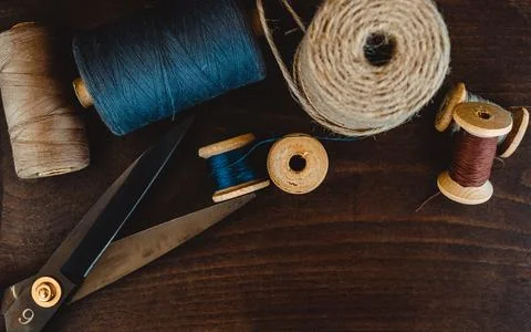Retro sewing tools: old scissors, bobbins of thread on gray fabric. Tailor's  Stock Photos