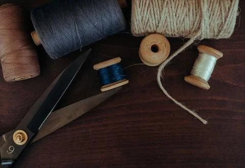 Retro sewing tools: old scissors, bobbins of thread on gray fabric. Tailor's  Stock Photos