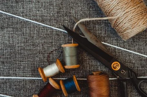 Retro sewing tools: old scissors, bobbins of thread on gray fabric. Tailor's  Stock Photos