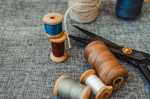 Retro sewing tools: old scissors, bobbins of thread on gray fabric. Tailor's  Stock Photos