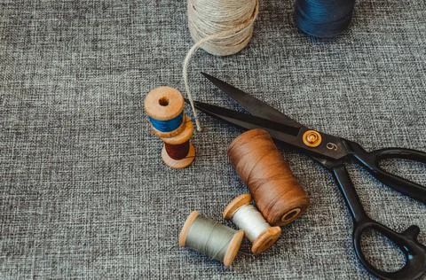 Retro sewing tools: old scissors, bobbins of thread on gray fabric. Tailor's  Stock Photos