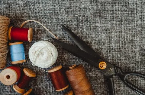 Retro sewing tools: old scissors, bobbins of thread on gray fabric. Tailor's  Stock Photos